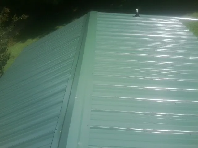 New green metal panels meeting at the ridge of a roof — Flat Roof Repair work by our crew in Alta Vista